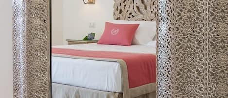 A bedroom with a bed, a nightstand, a lamp, and a decorative headboard.