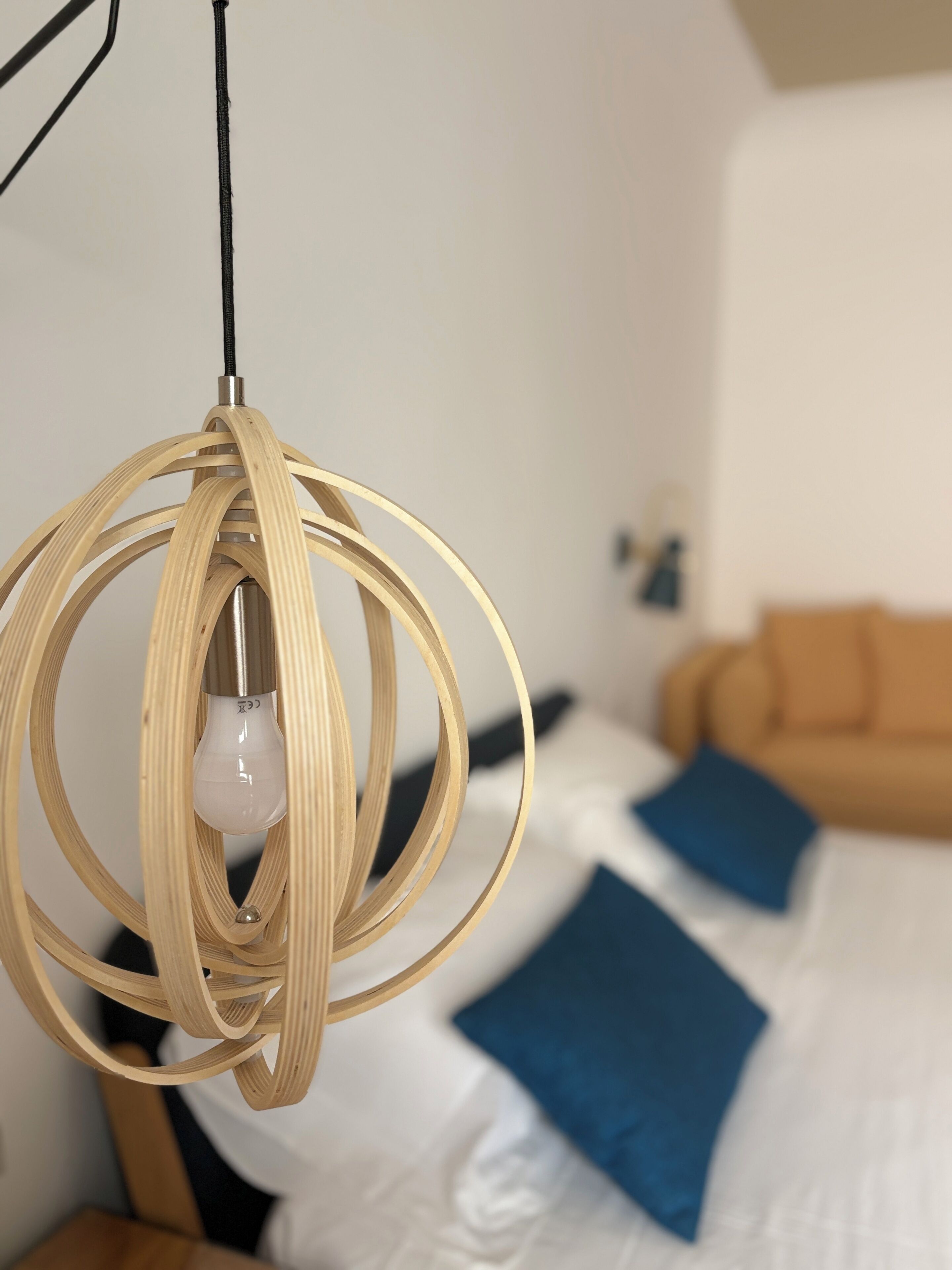 Ein modernes Schlafzimmer mit einem Bett, einer Pendelleuchte und einem an der Wand befestigten Nachttisch.