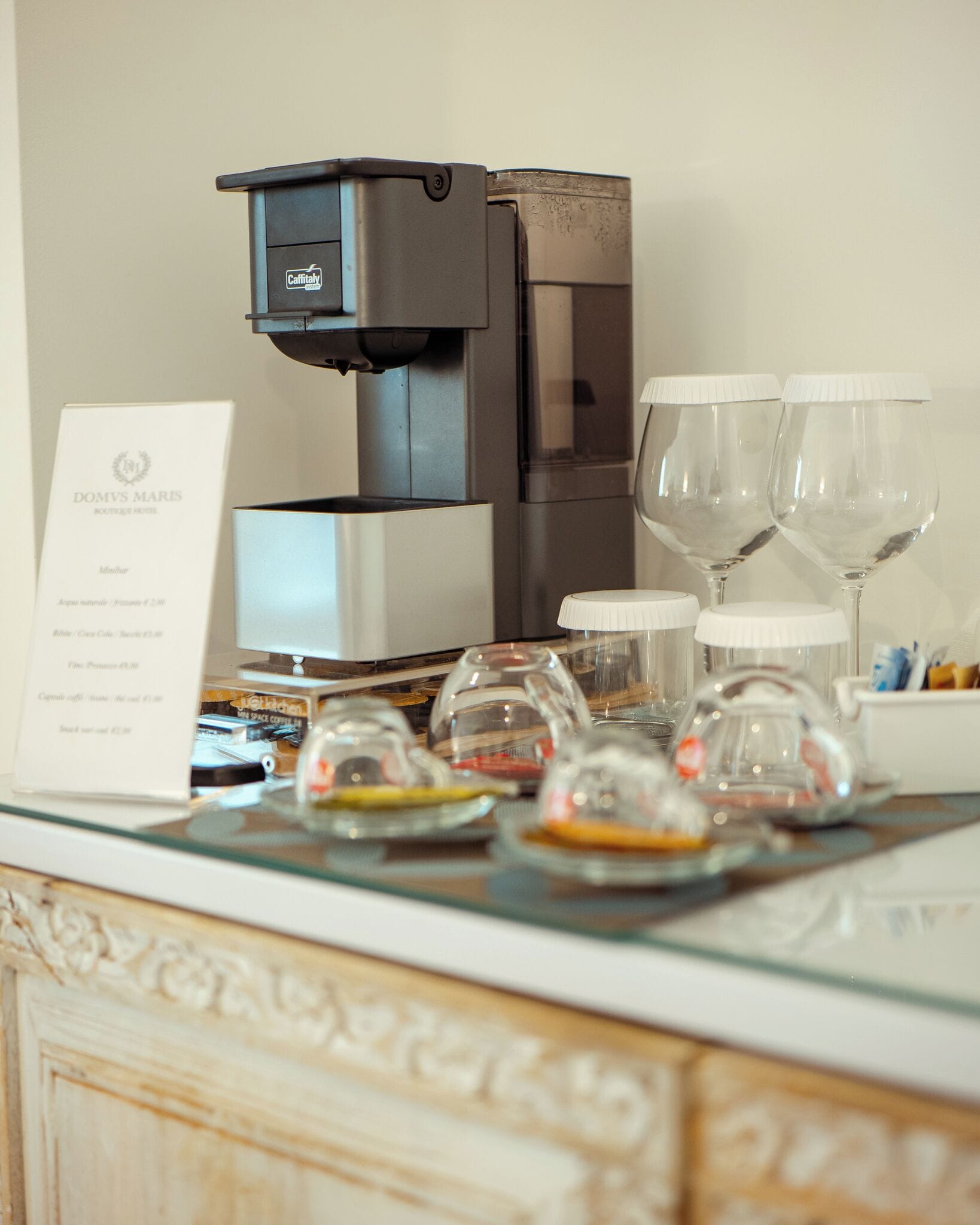 A breakfast setup with a coffee machine, wine glasses, and a menu.