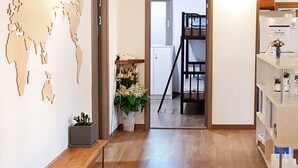 Een hal met houten vloer, een bankje, een wereldkaart decoratie, een potplant en een trap naar een andere kamer.