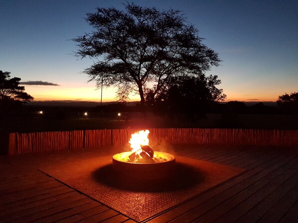 A fire pit in a circular stone structure with a wooden deck surrounding it.