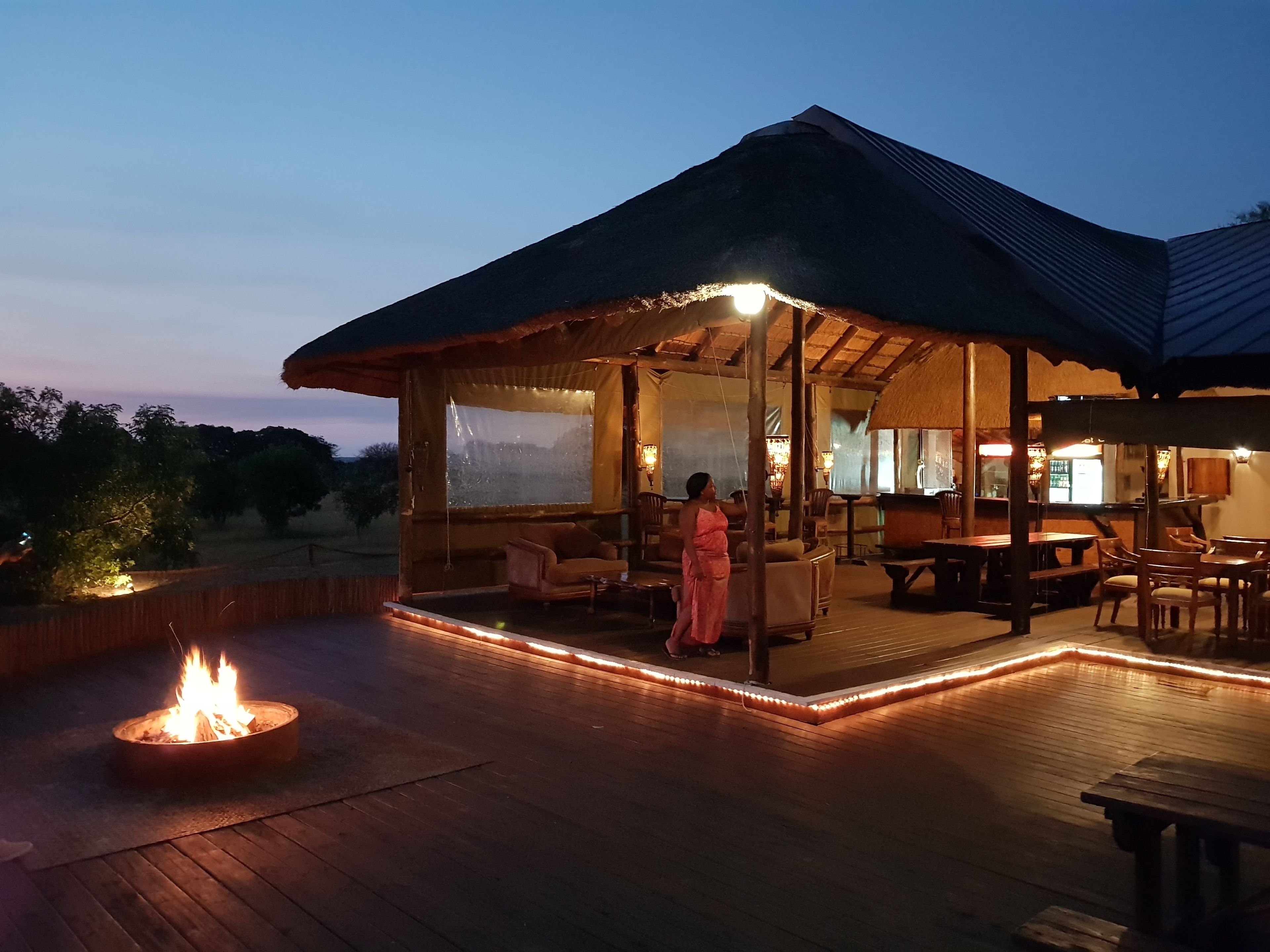A covered outdoor area with a fire pit, seating, and a view of the landscape.