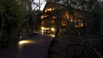 A wooden pathway leading to a lodge surrounded by trees.