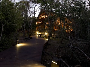 A wooden pathway leading to a lodge surrounded by trees.