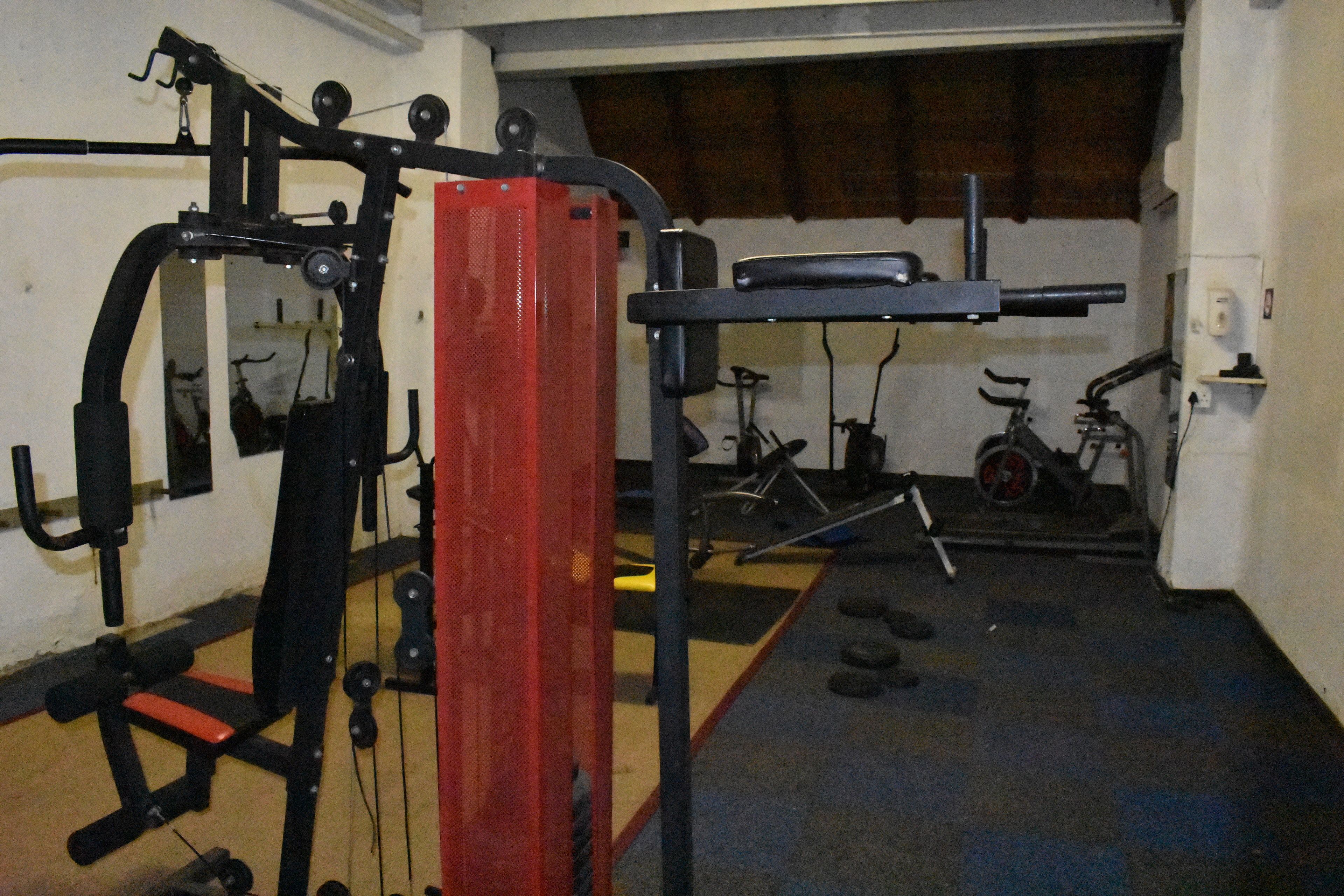 A gym with various exercise equipment, including a bench press, a squat rack, and a stationary bike.