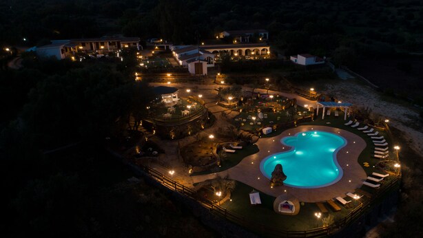 An aerial view of a resort with a swimming pool, lounge areas, and multiple buildings. - Country House S'Ozzastru (Dorgali)