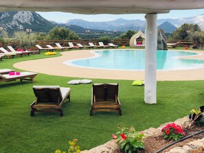 A pool area with lounge chairs and a view of mountains. - Country House S'Ozzastru (Dorgali)