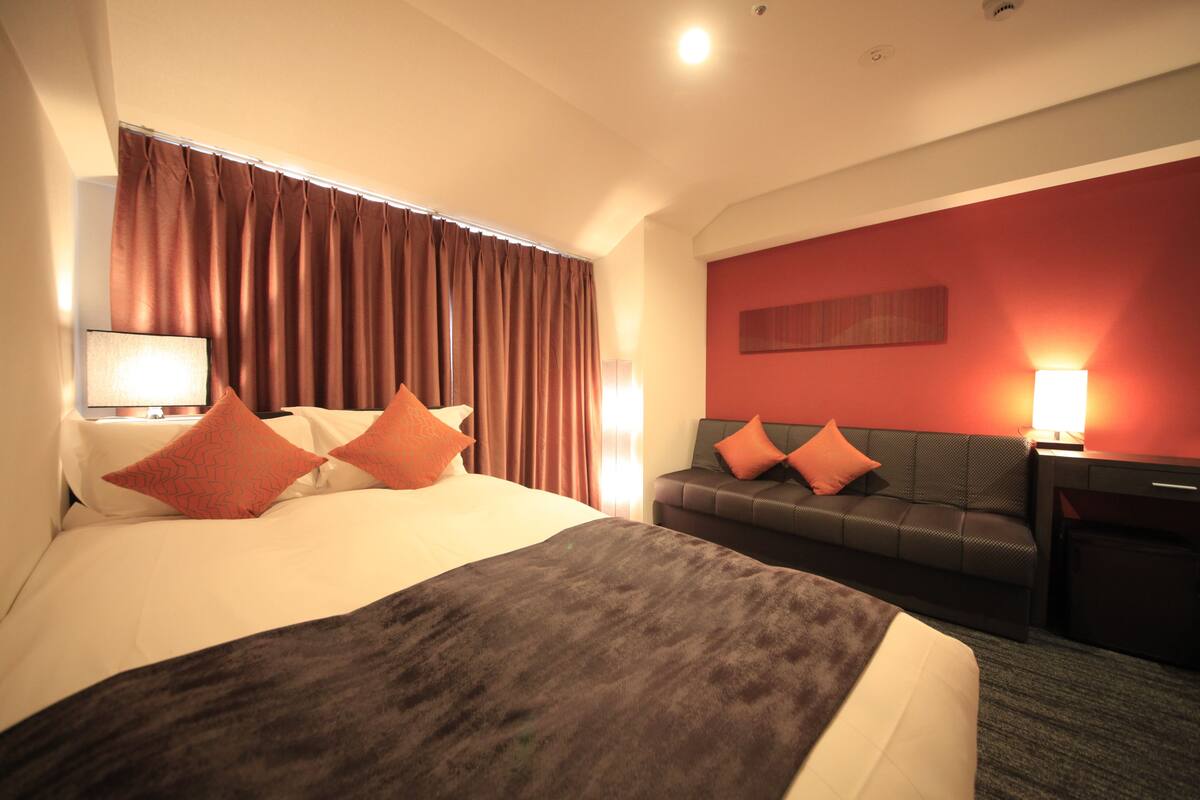 Habitación de hotel con una cama grande, un sofá, un escritorio y una pared de acento roja.