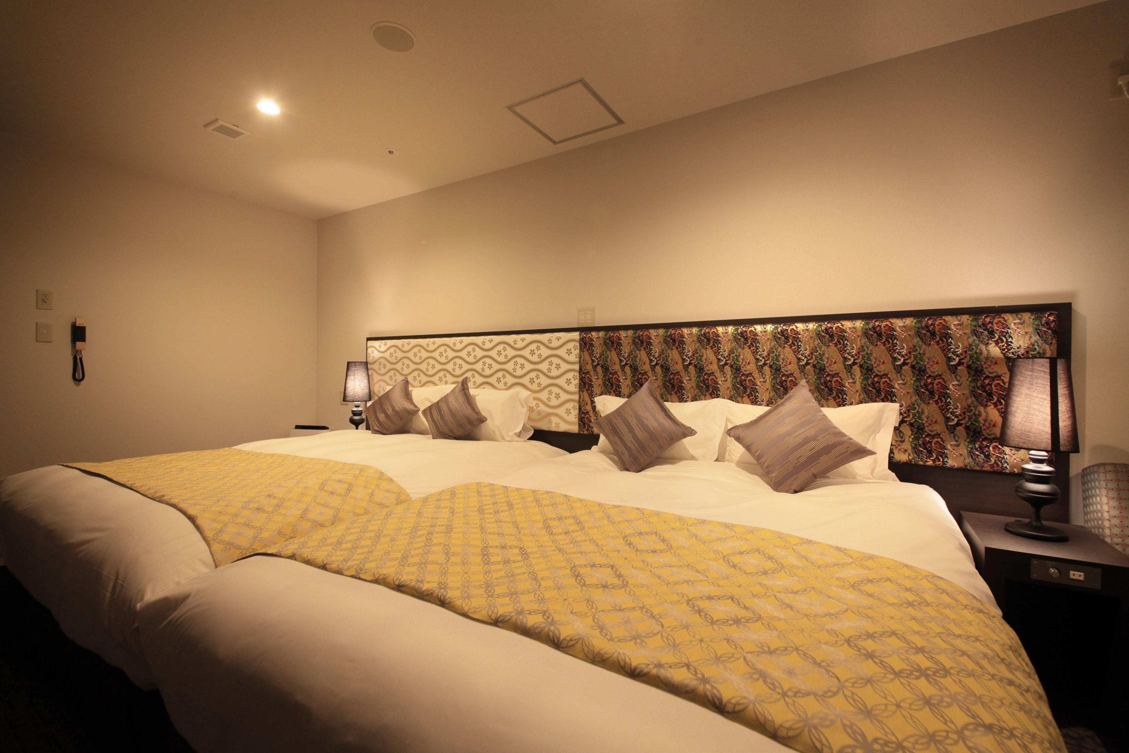 Una habitación de hotel con una cama grande, un cabecero estampado y una mesita de noche con lámpara.