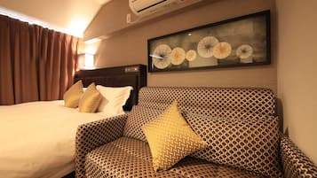 Een hotelkamer met een bed, een slaapbank en een luchtverkoeler aan de muur.