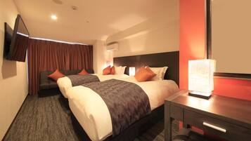 A hotel room with two beds, a desk, a chair, a TV mounted on the wall, and an air conditioning unit.