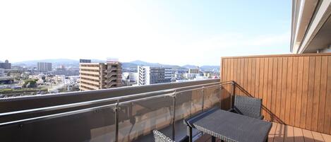 Un balcon offrant une vue sur le paysage urbain, avec des bâtiments et des montagnes en toile de fond.