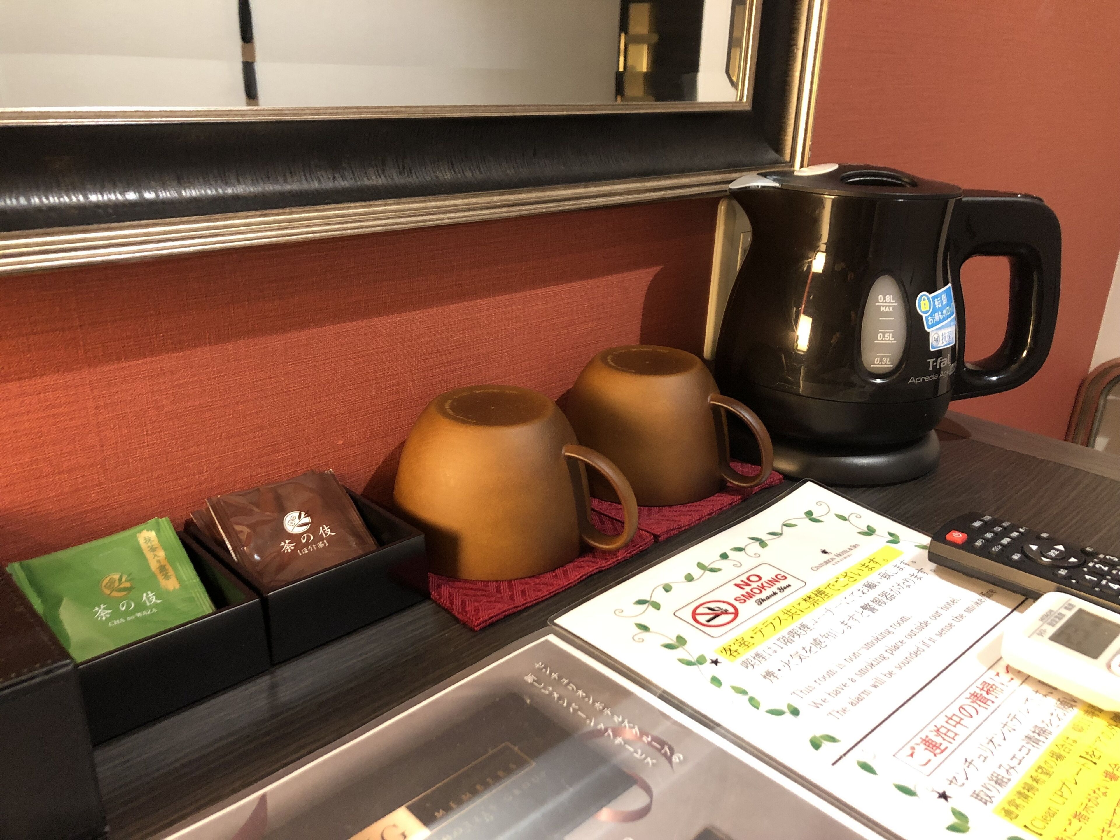 A hotel room with a table set with two teapots, a coffee maker, and a menu.
