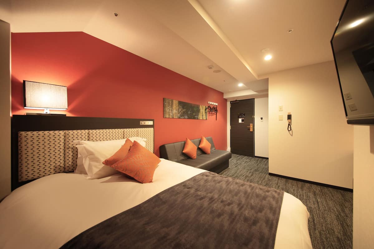 Habitación de hotel con una cama grande, un sofá, un televisor de pantalla plana y un cuadro en la pared.