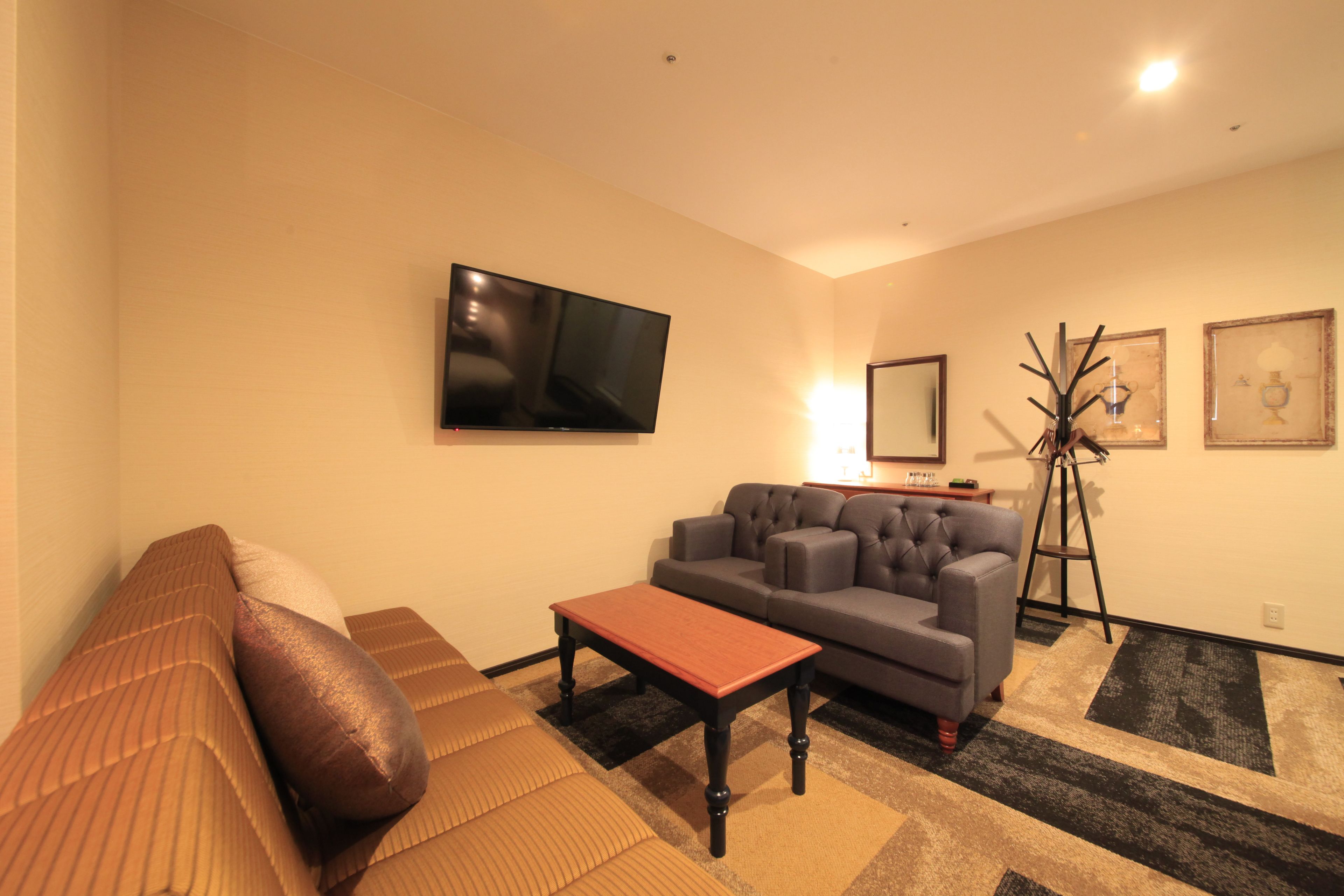 A living room with a sofa, a coffee table, a television, and a floor lamp.