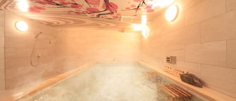 Un jacuzzi con un mural en el techo, paredes con azulejos y un banco de madera.