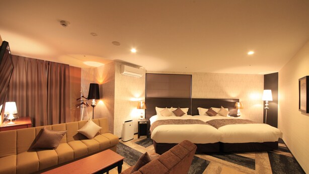 Habitación de hotel con una cama grande, un sofá, una mesita y dos lámparas.