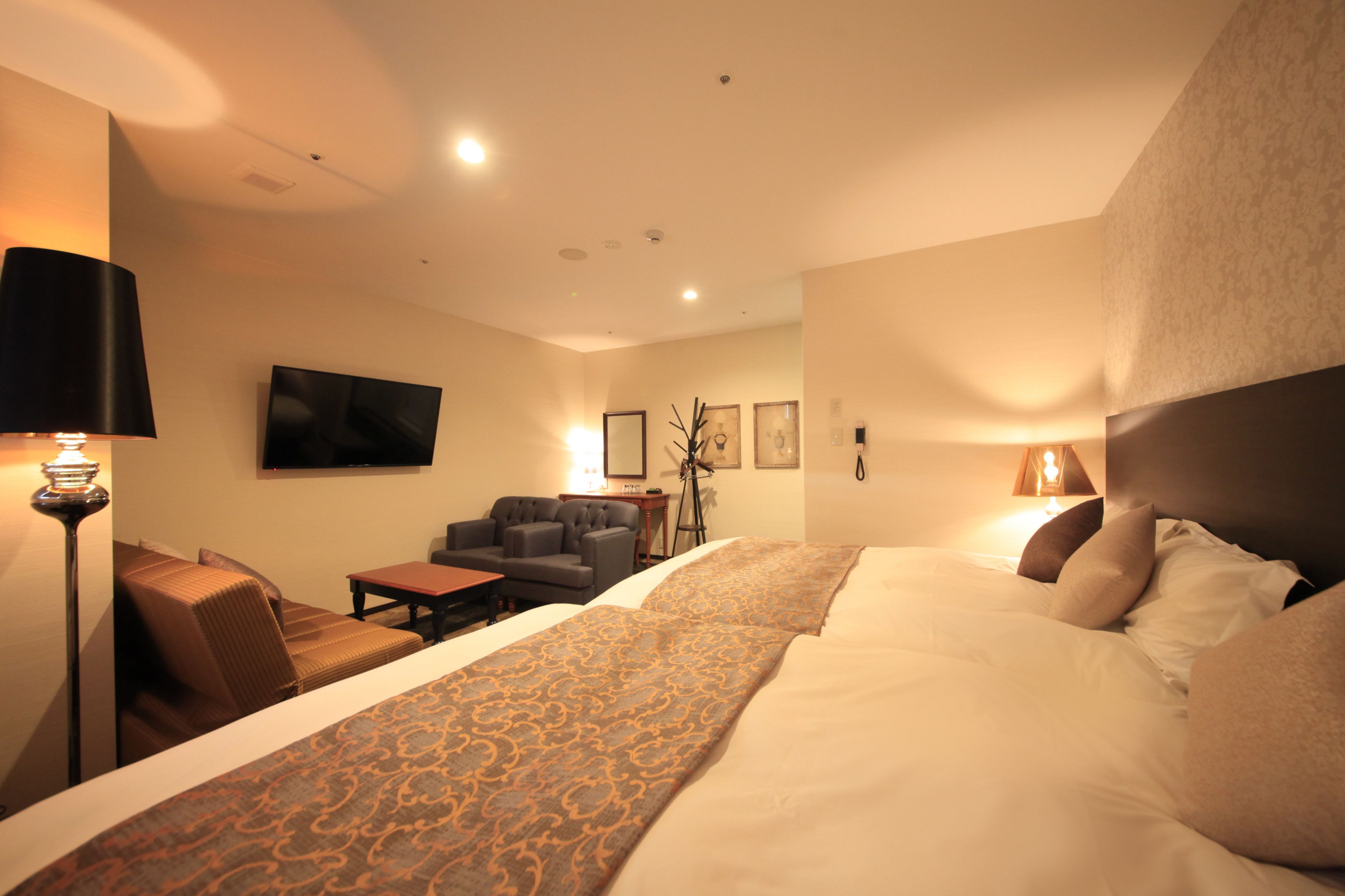 Ein Hotelzimmer mit einem großen Bett, einer Sitzecke, einem Schreibtisch und einem an der Wand montierten Fernseher.