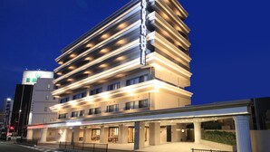 Un hotel de varios pisos con un diseño moderno, que cuenta con una entrada destacada y una fachada bien iluminada.