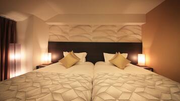A double bed with a geometric patterned bedspread, two bedside lamps, and a textured wall headboard.