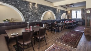 A restaurant with dark wood furniture, stone walls, and a large rug. - Hotel Il Mulino (Seekirchen am Wallersee)