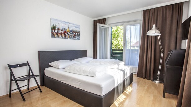 A modern hotel room with a bed, a desk, a chair, and a painting on the wall. - Hotel Il Mulino (Seekirchen am Wallersee)