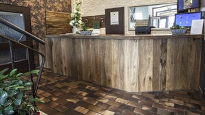 A reception desk with a wooden finish, a clock, and a floral arrangement. - Hotel Il Mulino (Seekirchen am Wallersee)