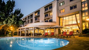 Un hotel con piscina, mobiliario exterior y una zona cubierta.