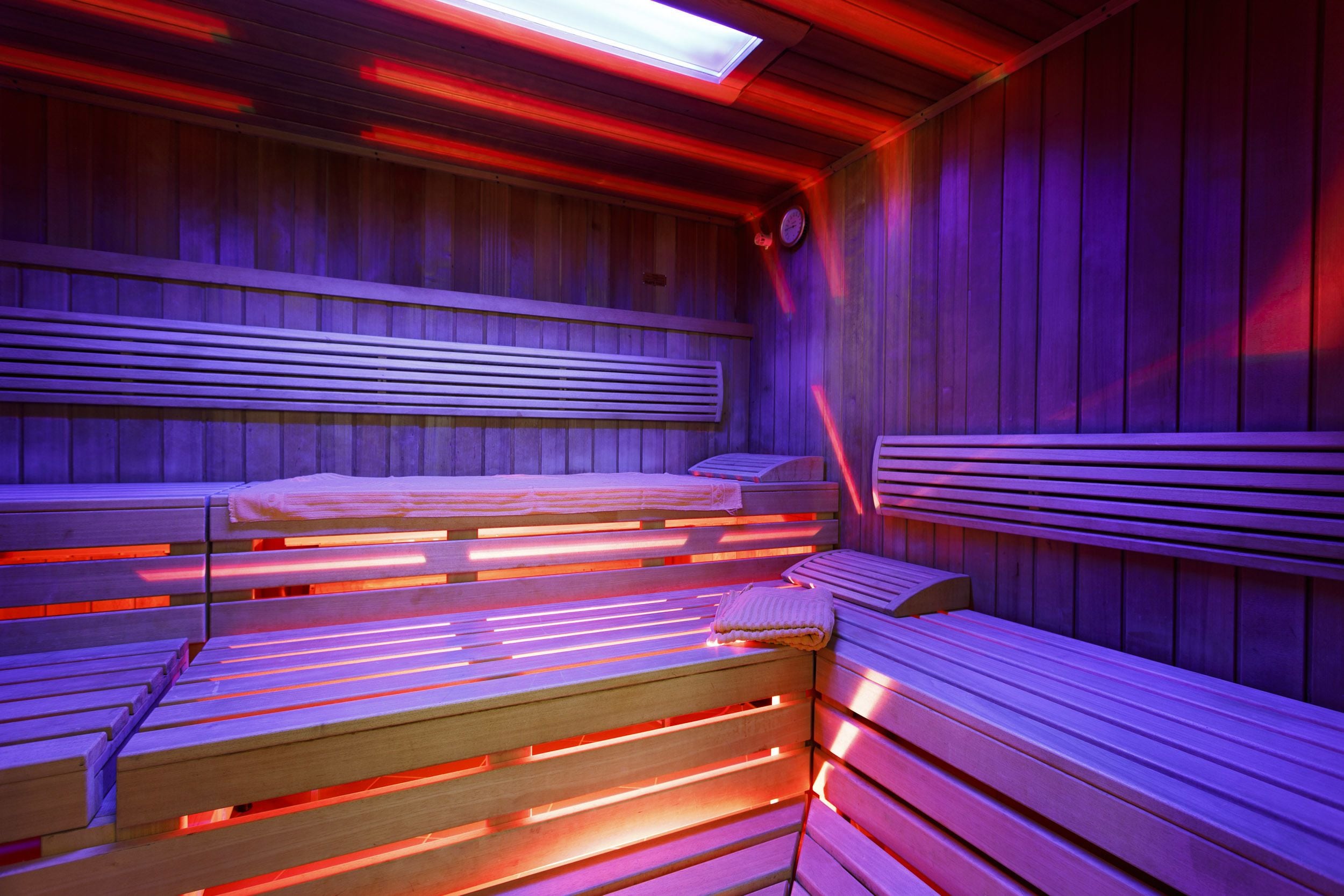 A sauna with wooden benches and red lighting.