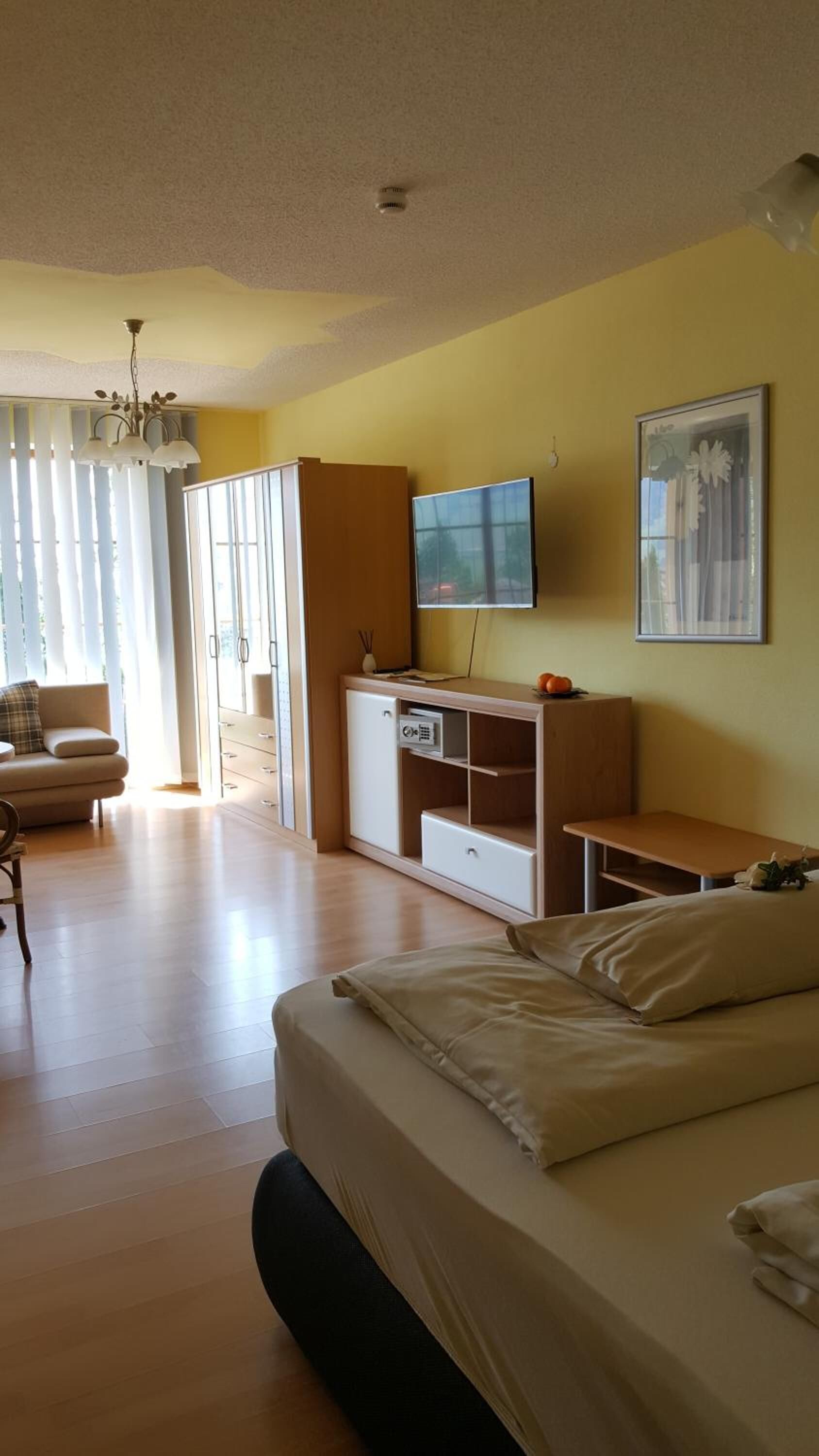 Una habitación de hotel con cama, televisor, escritorio y silla.