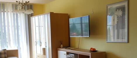 Una habitación de hotel con cama, televisor, escritorio y silla.