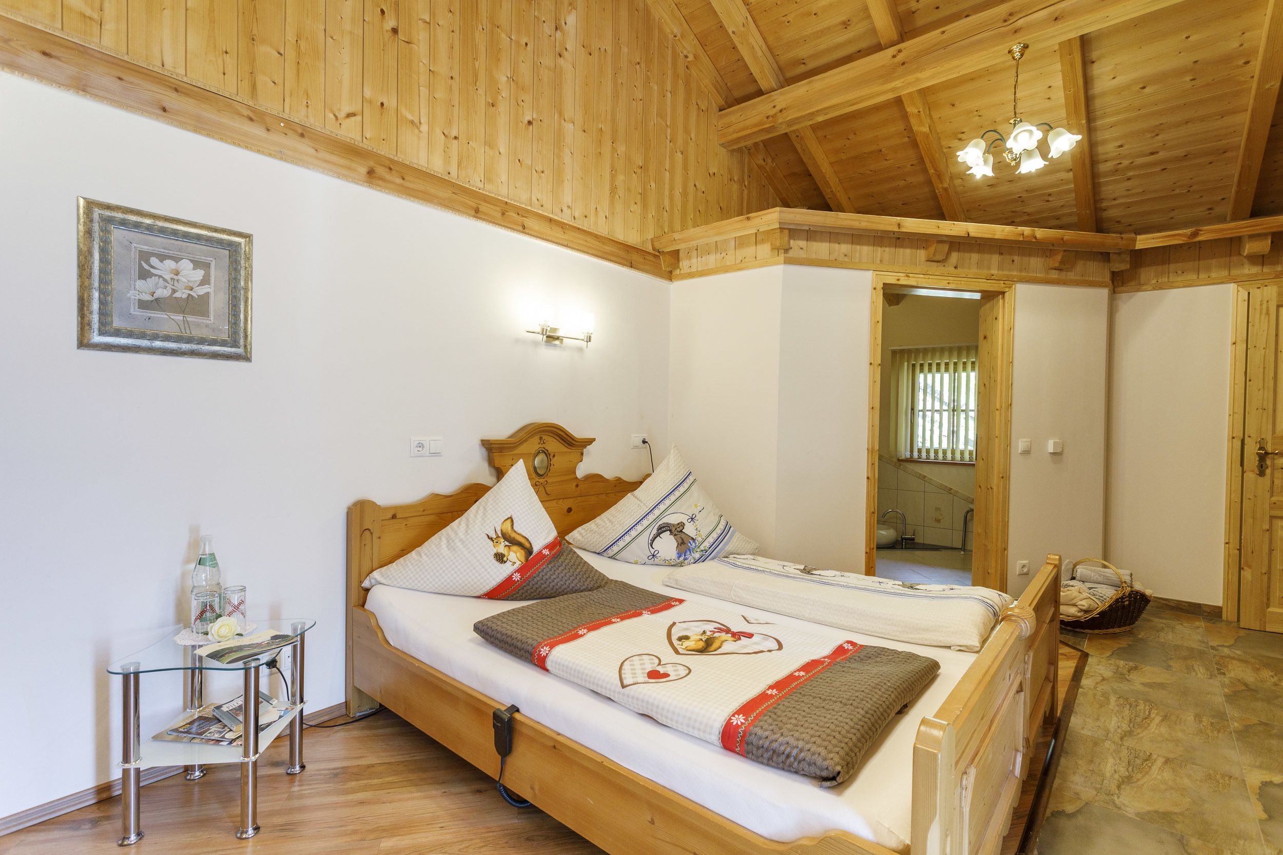 Een kamer met houten lambrisering, een bed, nachtkastje en een spiegel.