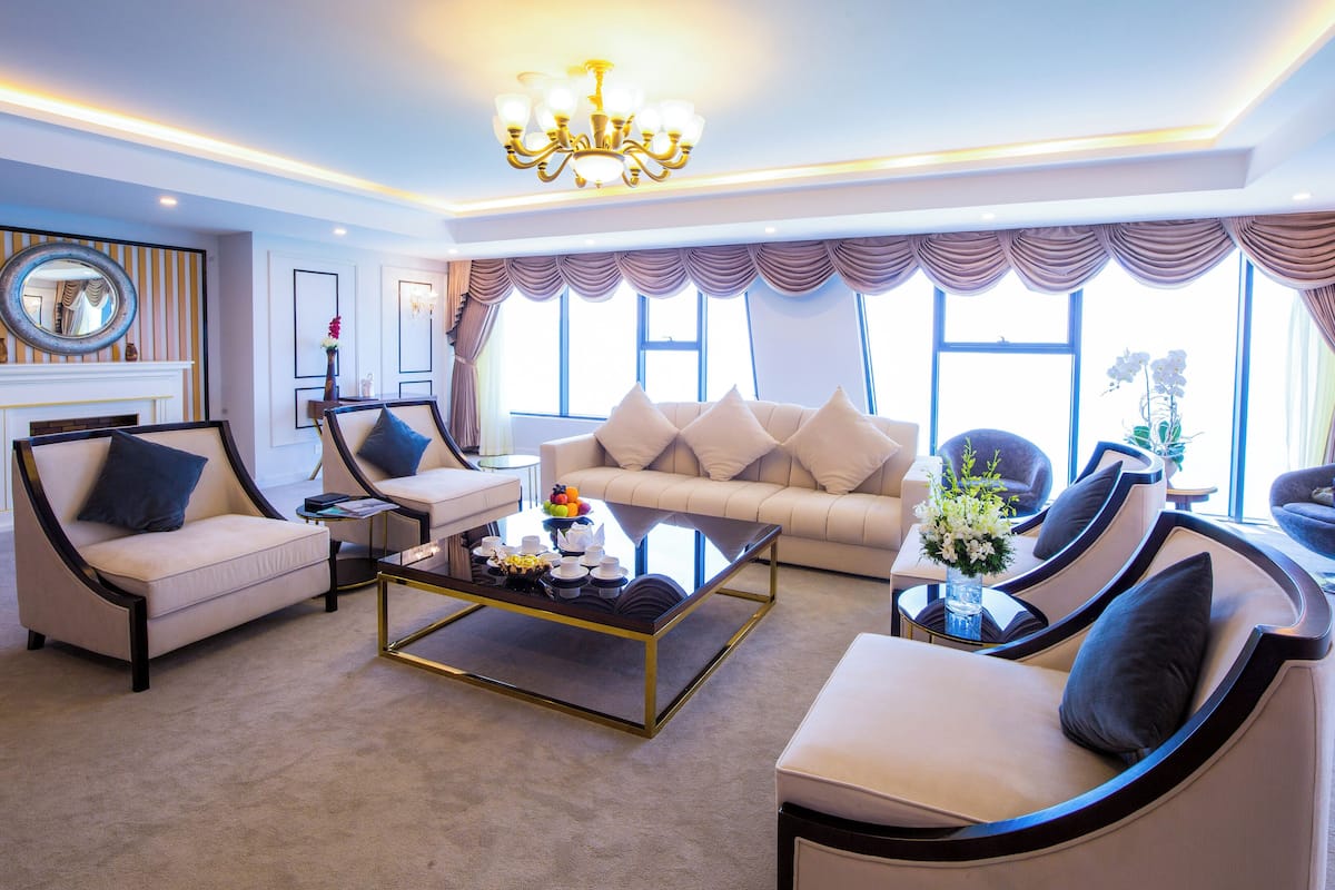 A modern living room with a sofa, armchairs, a coffee table, and a chandelier.
