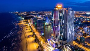 A high-rise hotel with a prominent rooftop sign, surrounded by a coastal cityscape at night. - Muong Thanh Luxury Da Nang Hotel (Da Nang)