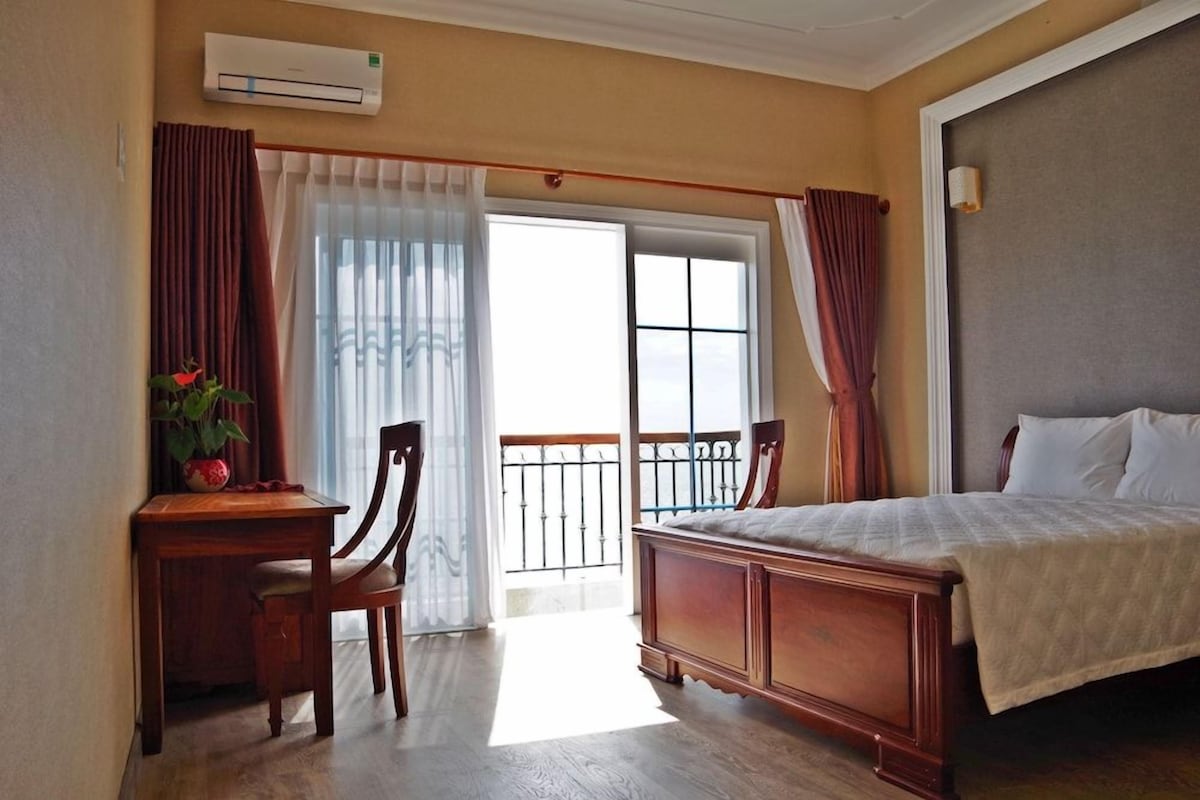 Une chambre d’hôtel équipée d’un lit, d’un bureau, d’une chaise, d’un appareil de climatisation et offrant une vue par la fenêtre.