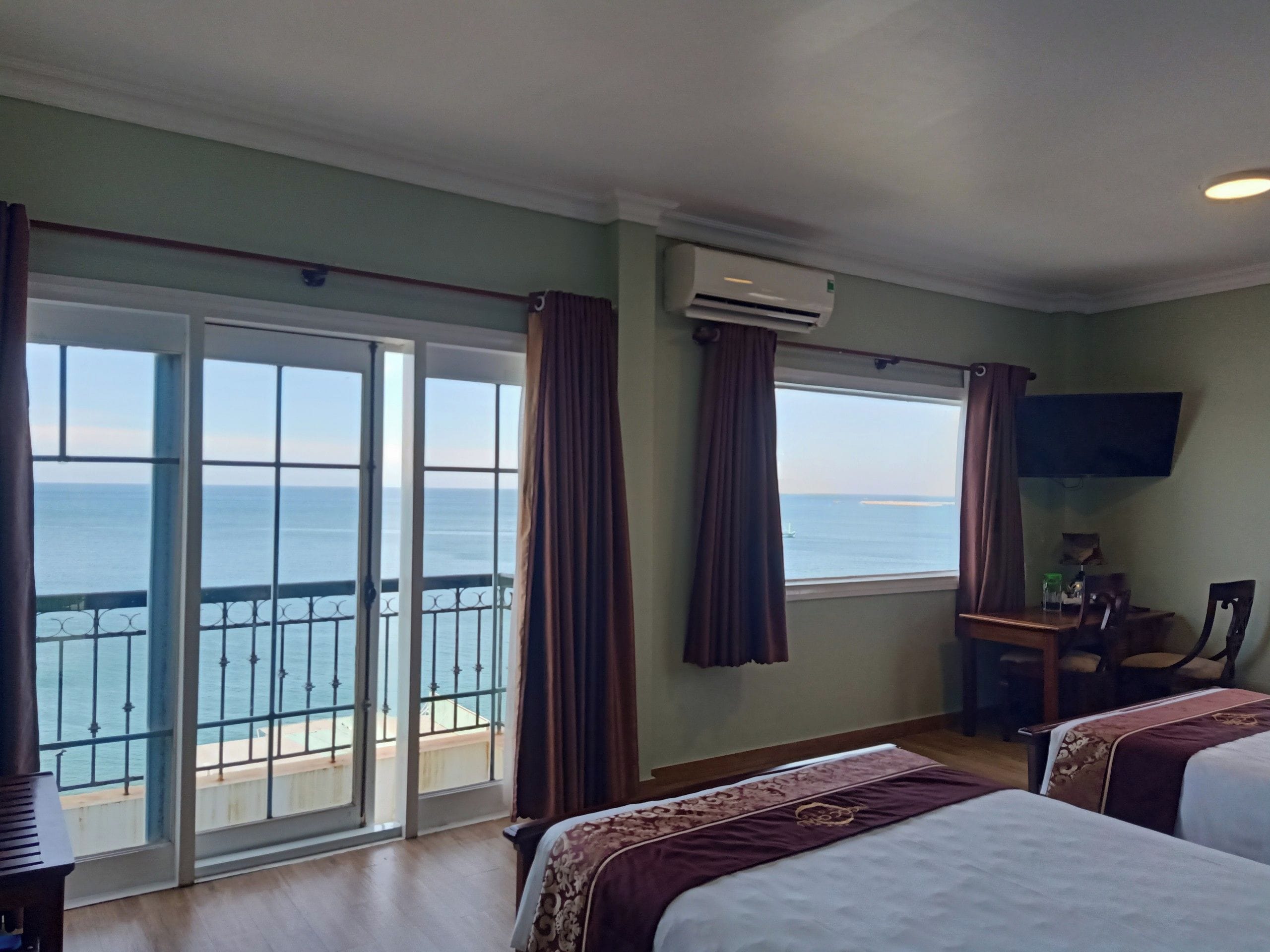 Une chambre d’hôtel avec un balcon, un lit, un bureau et une télévision.
