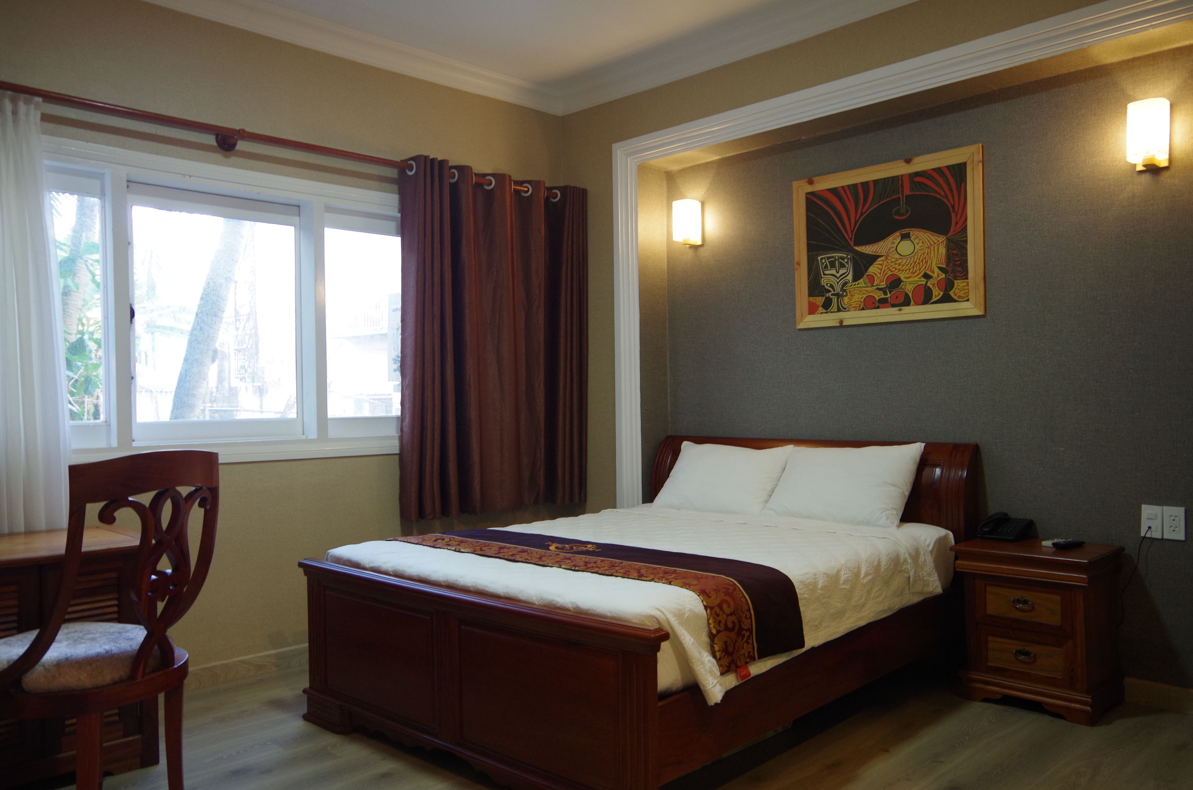 A bedroom with a wooden bed, a nightstand, a chair, and a painting on the wall.