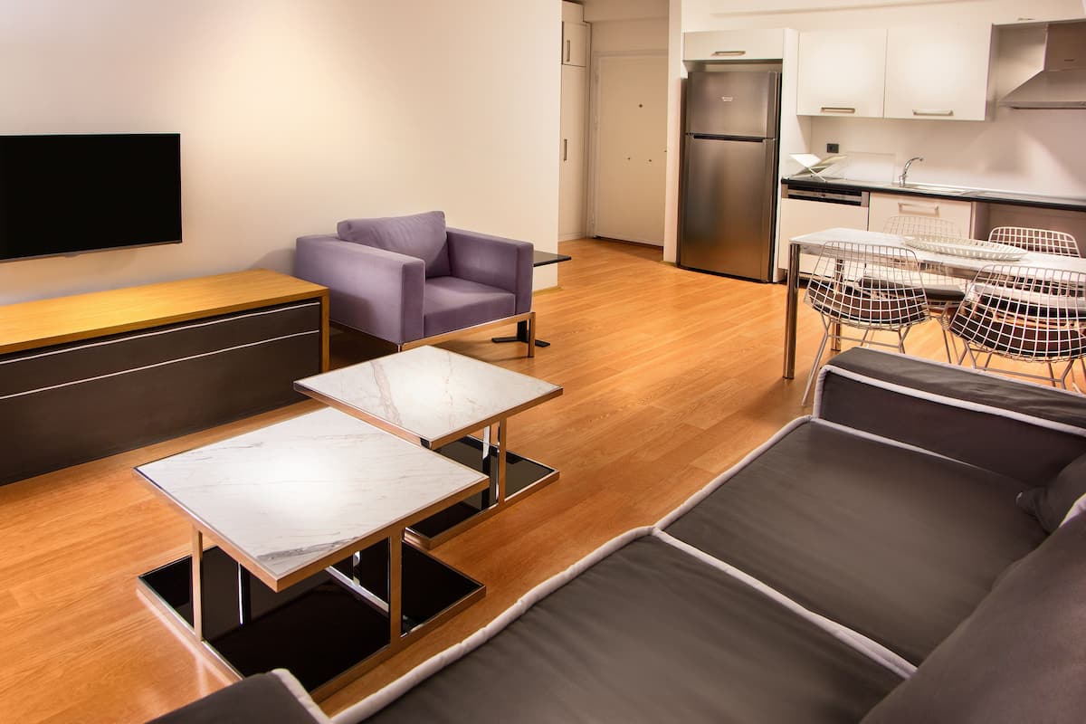 A modern living room with a sofa, two tables, a TV, and a purple armchair.