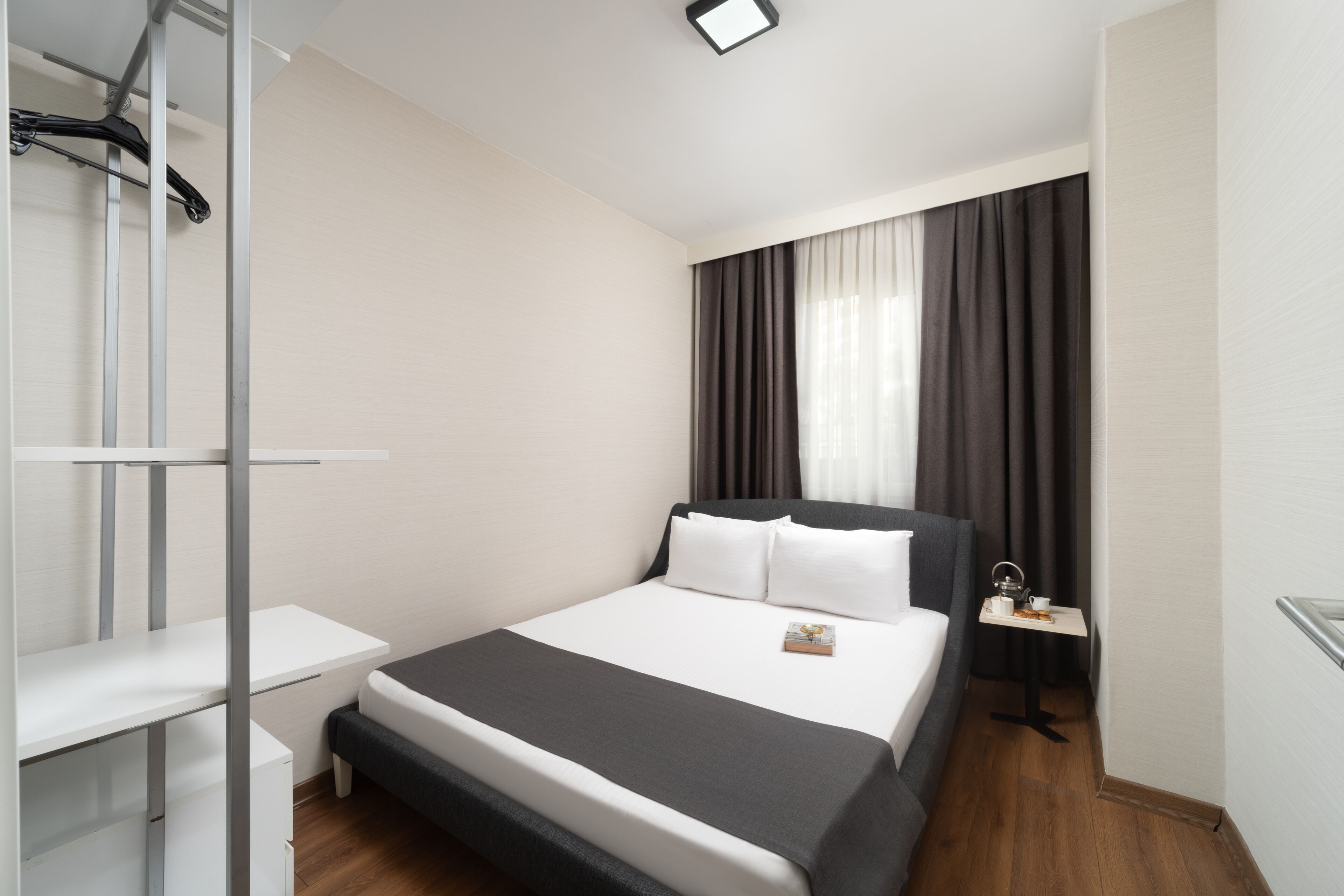 A modern hotel room with a bed, bedside table, and a small desk.