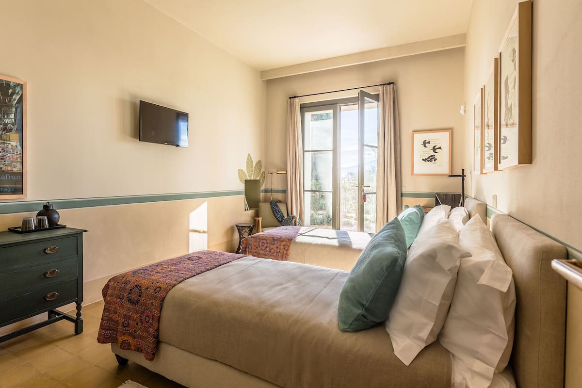 A bedroom with a bed, bedside table, and a window with curtains.