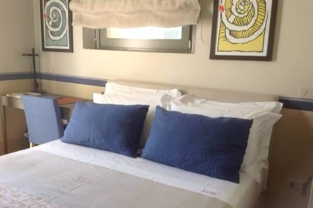A hotel room with a bed, two pillows, a nightstand, a lamp, and artwork on the walls.