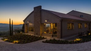A modern house with a brick facade, large windows, and a gravel driveway. - A440 in Tuscany (Pienza)