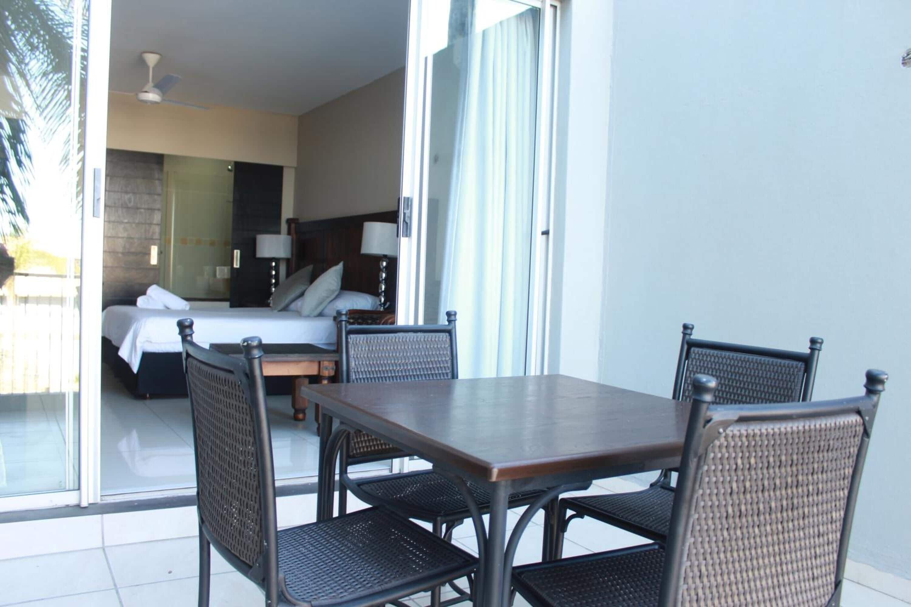 Una habitación de hotel con una cama, un escritorio y un área de comedor con sillas.