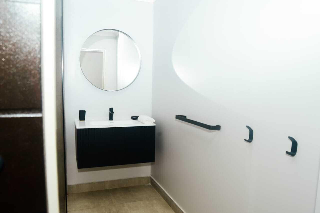 Une salle de bain avec un lavabo blanc, un miroir et un porte-serviettes.