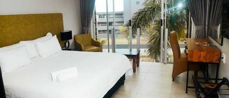 A hotel room with a large bed, a desk, a chair, and a TV.