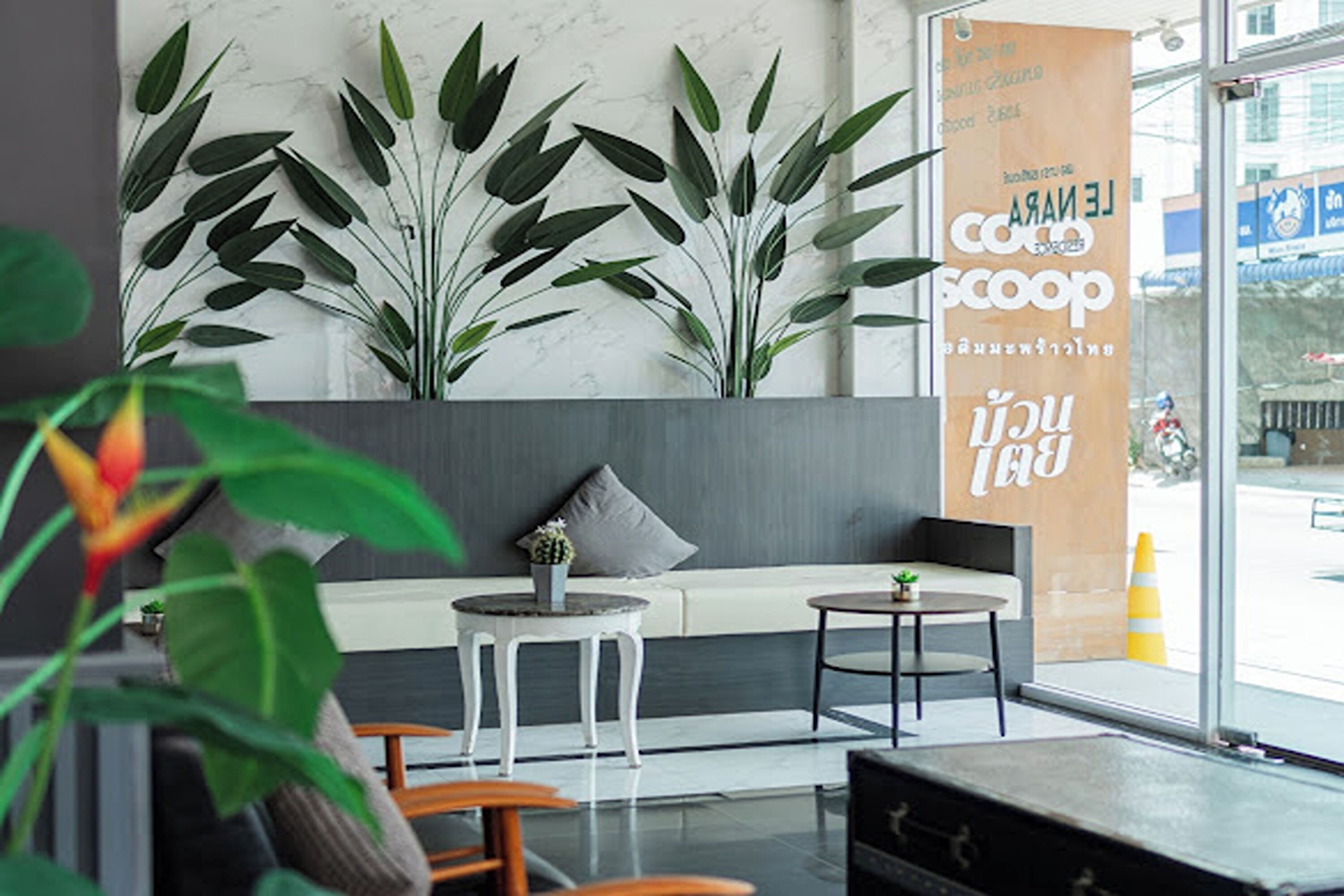 A modern interior with a seating area, large potted plants, and a banner.