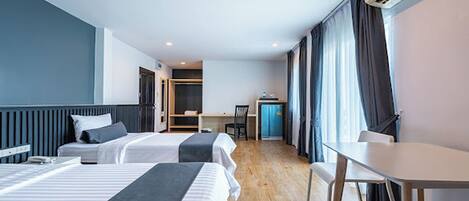 Een hotelkamer met twee bedden, een bureau, een stoel en een kleine kitchenette.