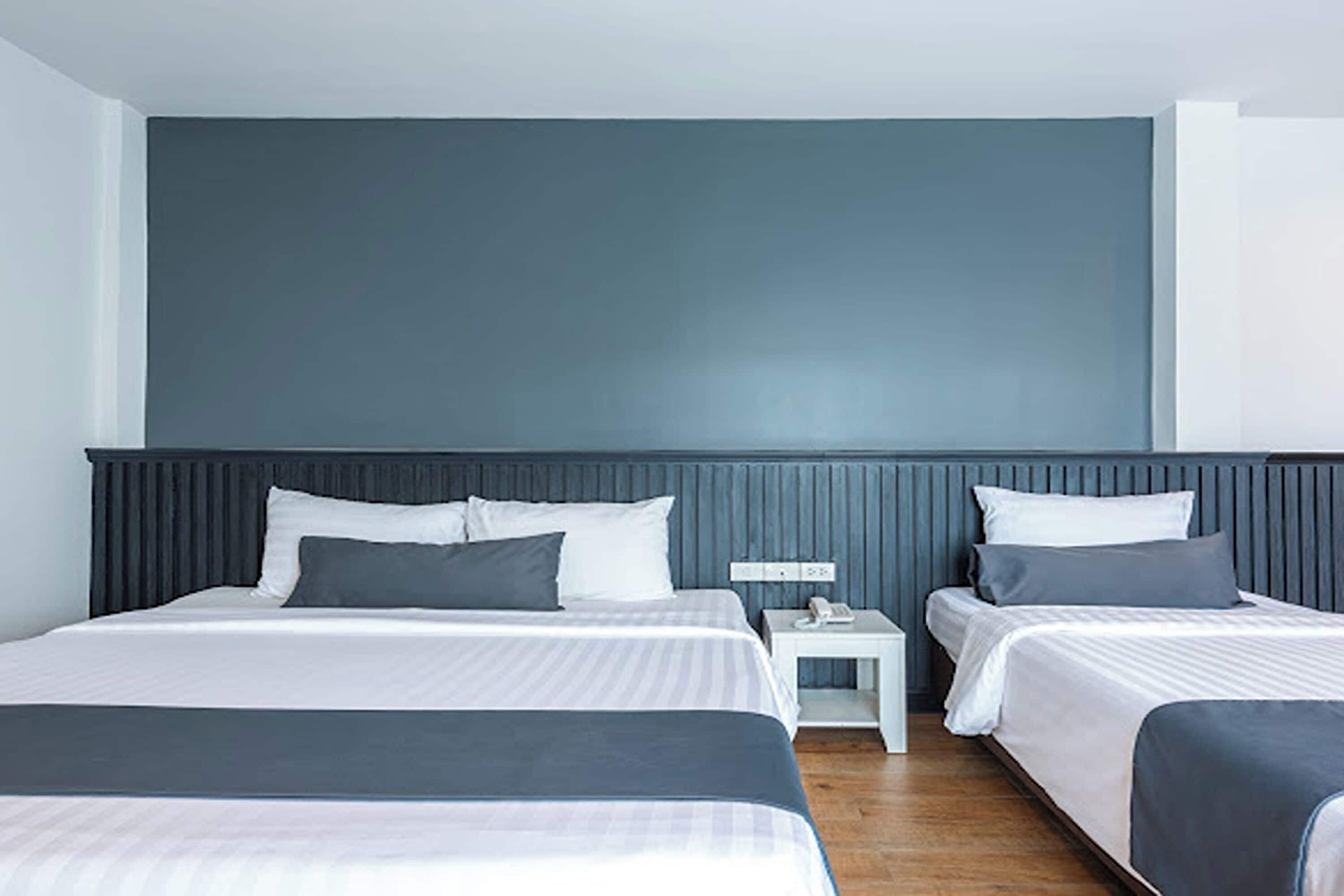 Habitación de hotel con dos camas, una mesita de noche y un teléfono en la pared.