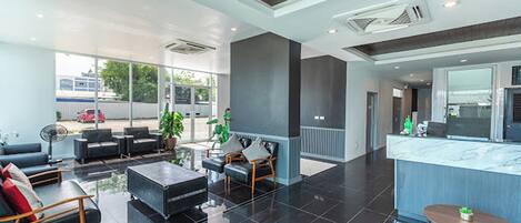 Un moderno vestíbulo de hotel con una zona de estar, una recepción y vistas al exterior.