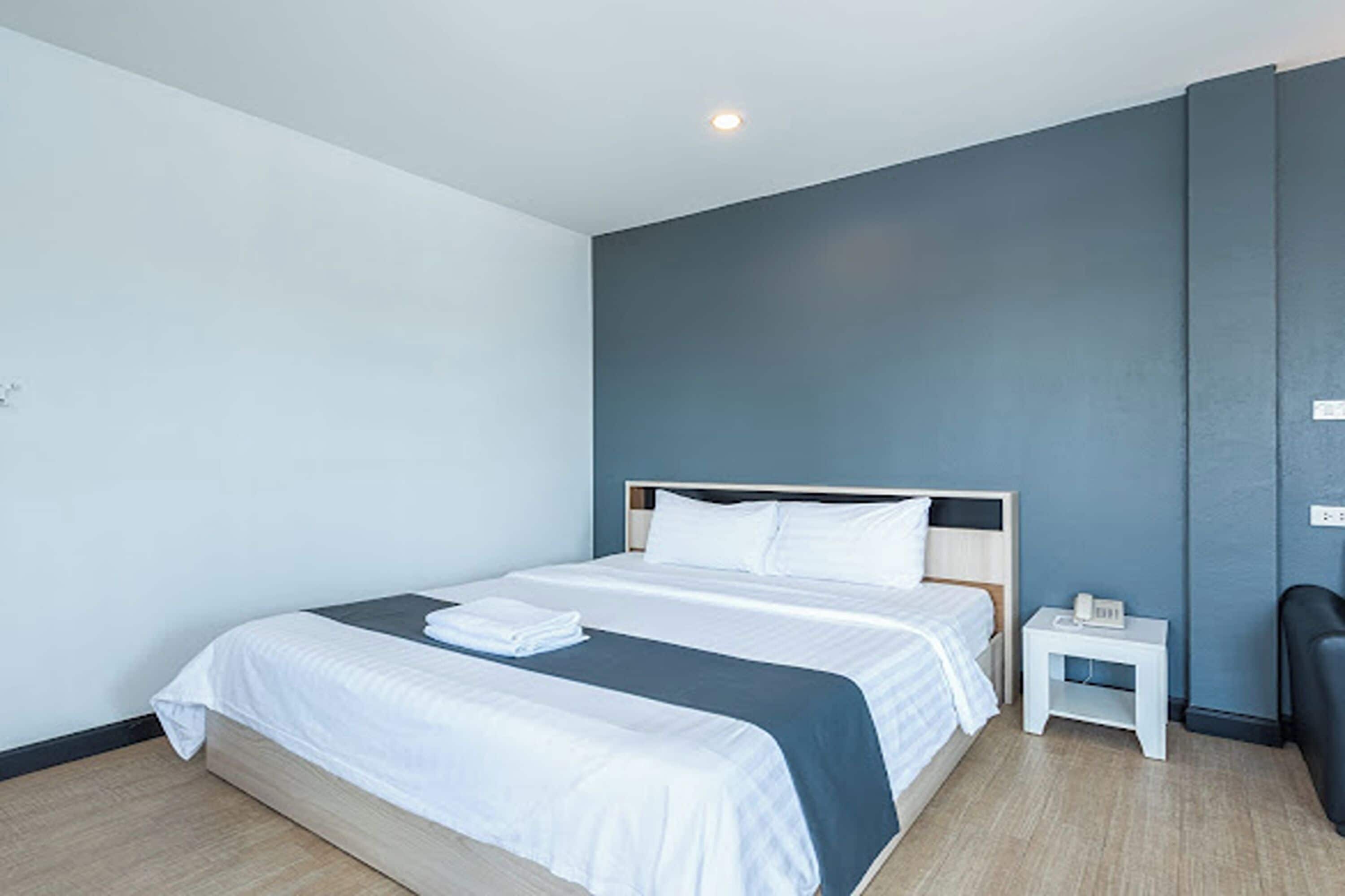 A modern hotel room with a bed, bedside table, and a chair.